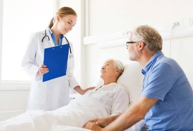 A doctor speaking with an elderly patient and a family member at the bedside