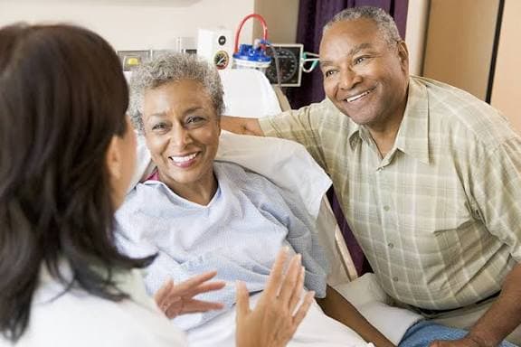A smiling care provider assisting a patient in a hospital hallway