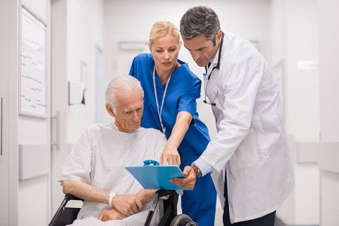 A nurse gently holding the hand of an elderly patient