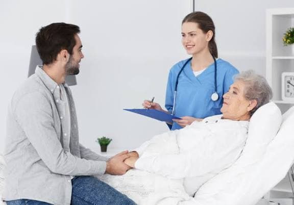 A care provider attending to a patient recovering in a hospital bed
